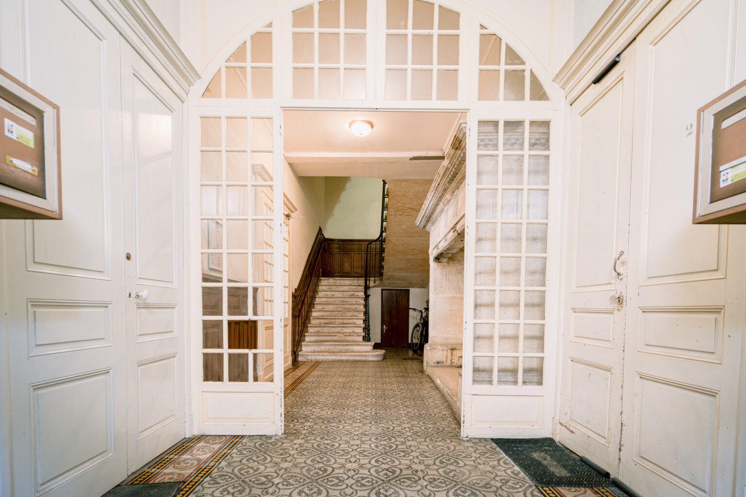 Entrée intérieure, caractérisée par une magnifique arche et un escalier époque ancienne en fond. Une invitation à découvrir un lieu d'exception.