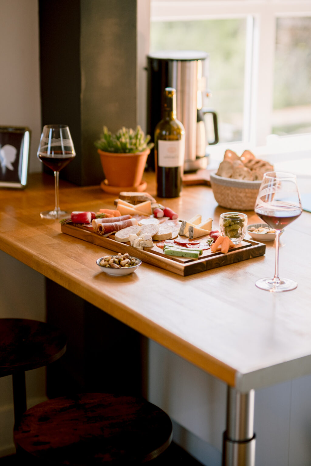 Plateau de charcuterie alléchant, accompagné de deux verres de vin et d'une bouteille sur une table en bois.