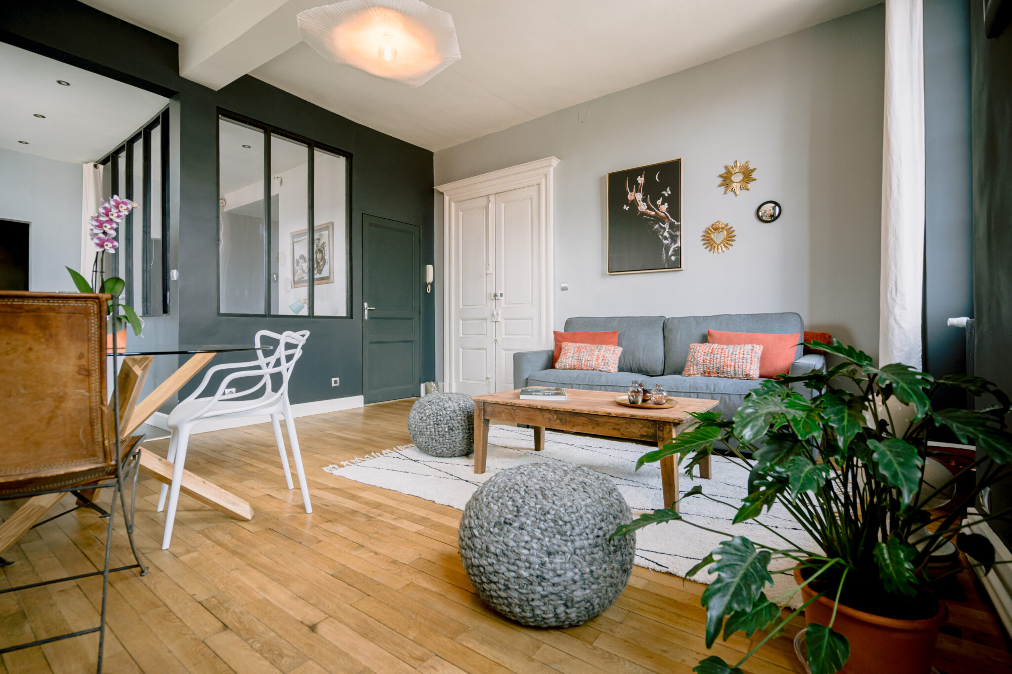 Vue complète sur le salon de l'Oasis d'Albi, mettant en scène son canapé convertible, sa table basse, un pouf, ainsi que la table et la verrière. Un espace harmonieux pour des moments de détente.