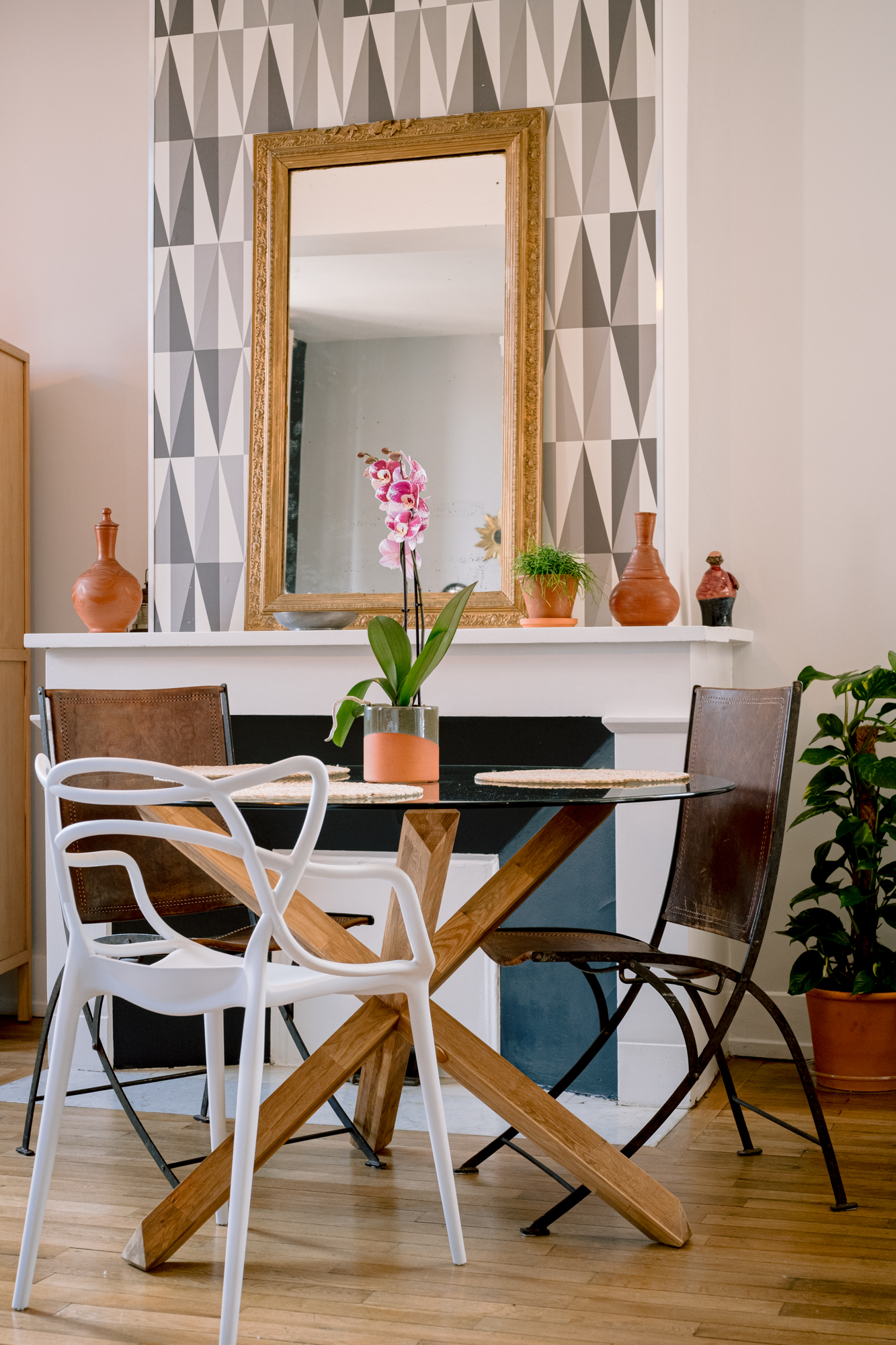 Élégante table à manger en verre avec pied en bois, trônant dans le salon, cheminée en arrière-plan. L'alliance parfaite de la modernité et de la chaleur.