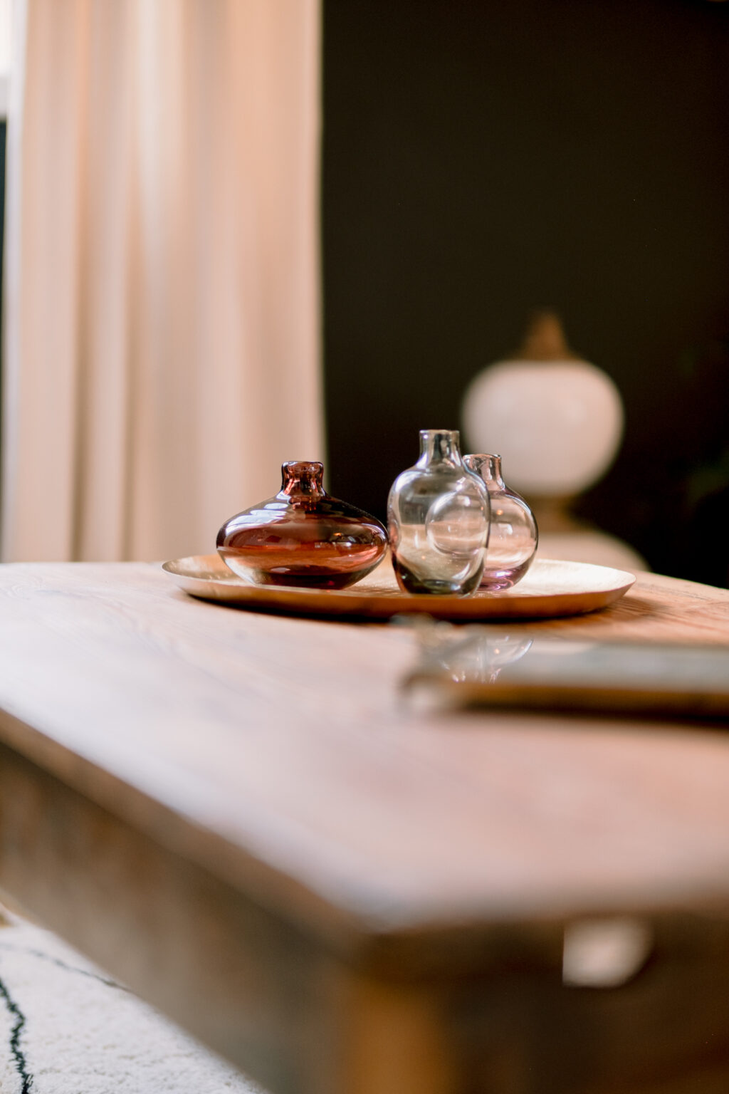 Plateau de vases colorées en verre transparent, apportant une touche zen, posé sur un plateau en bois, lui-même sur une table en bois. Équilibre harmonieux et esthétique apaisante.